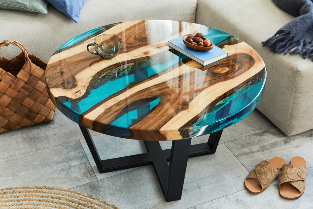 Round epoxy resin live edge table in Ottawa with natural wood grain and turquoise river design, styled in a modern living room.