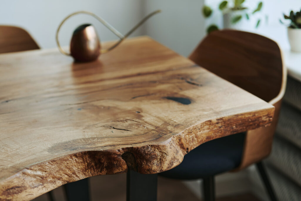 Close-up of a handcrafted live edge table in Ottawa with natural wood grain, rustic edge details, and modern chairs.